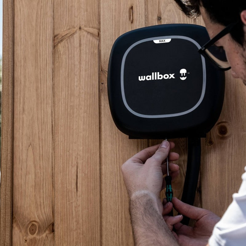 A black Wallbox Pulsar Max installed on a wooden wall.